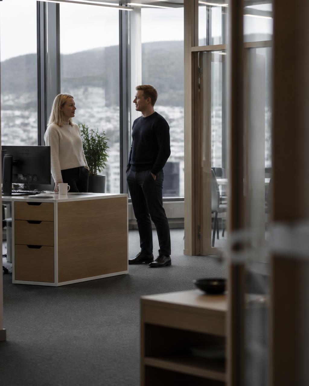 To kolleger i samtale på et norsk kontor